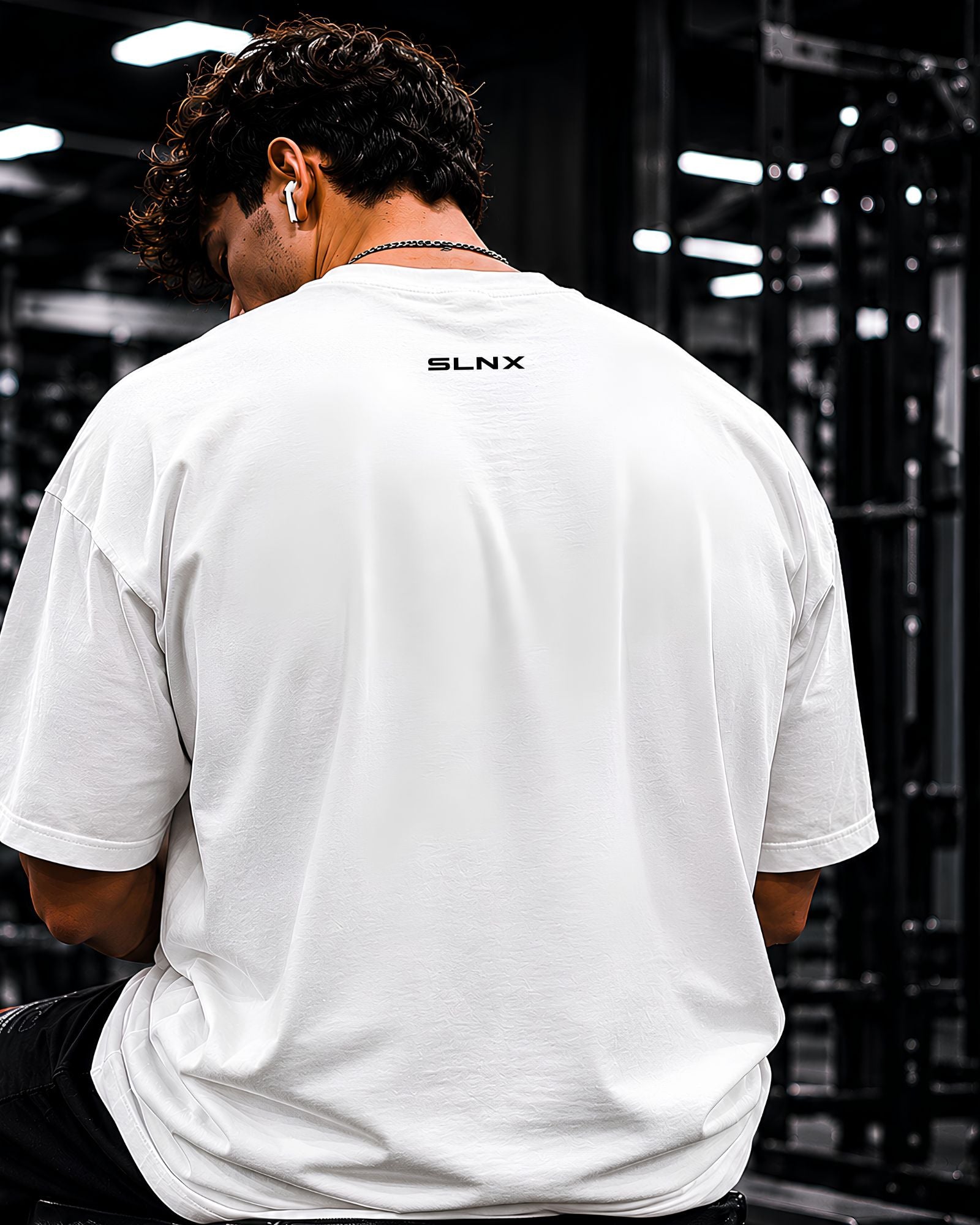 Modelo usando polo oversized NO EXCUSES JUST RESULTS para gym y streetwear ESPALDA